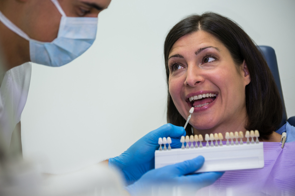 Dentist examining female patient with teeth shades<br />
