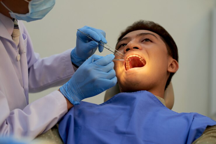 Young man sitting mouth wide open at the office of dentist at the annual examination<br />
